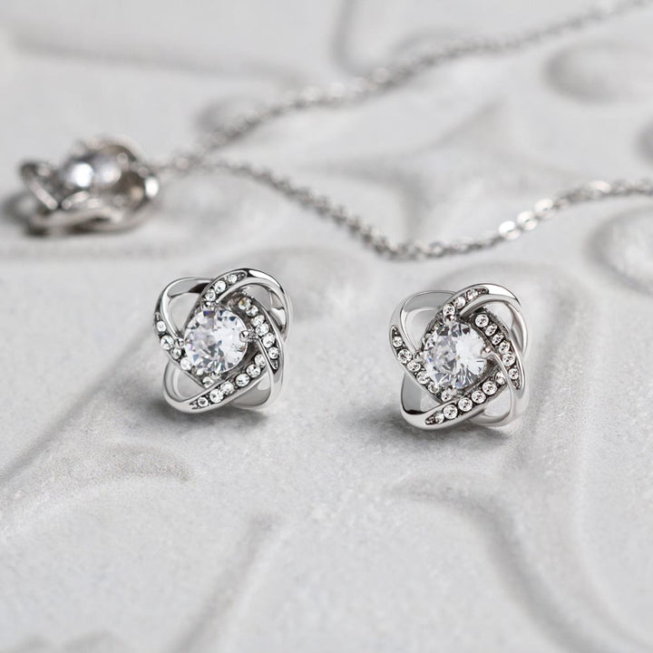 Love Knot Earring & Pendant Necklace Set. 14k white gold over finish surrounding a dazzling 6mm cubic zirconia crystal.